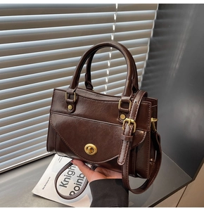 Close-up of retro dark brown leather handbag with gold metal clasp and top handle