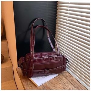 Detailed macro of burgundy retro underarm bag with glossy leather and metallic buckles