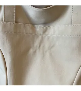 Macro shot of Midolai brand logo embroidery on a minimalist beige canvas bucket bag