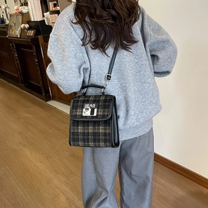 Détail du sac à main vintage à carreaux marron avec écusson ours et lanières cuir