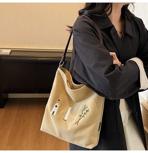 Detail of vintage canvas tote bag featuring floral embroidery and dark brown leather straps