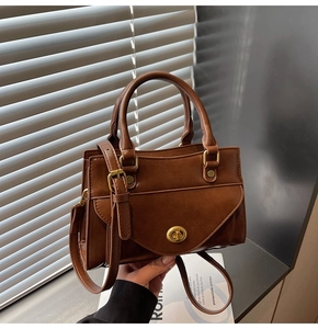 Detailed view of the brown leather vintage handbag with elegant gold twist lock and handle