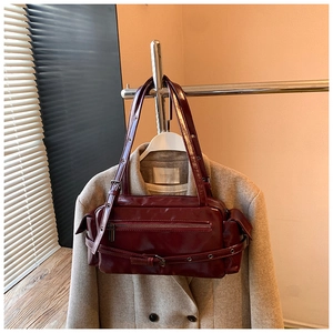 Detail of burgundy glossy leather bag with zipper and adjustable buckle straps