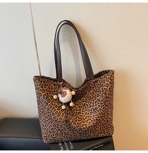Détail du cabas en toile léopard avec bandoulières en cuir et breloque pelucheuse