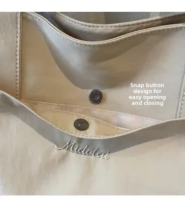 Detail of the magnetic buckle closure on a khaki canvas bag with Midolai embroidery