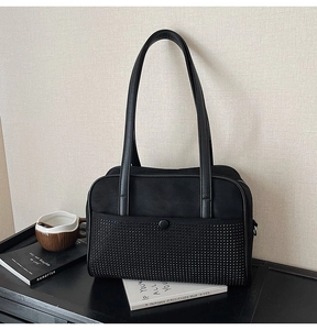 Detail of a black matte shoulder bag featuring stylish tonal studs and leather handles