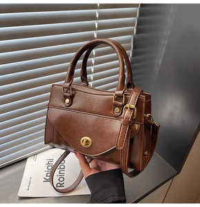 Detail of vintage brown square handbag featuring a gold round twist lock and flap cover
