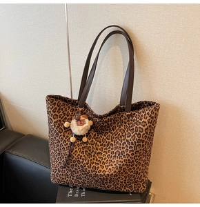 Détail du sac cabas léopard avec un pendentif ours en peluche blanc et des anses marron
