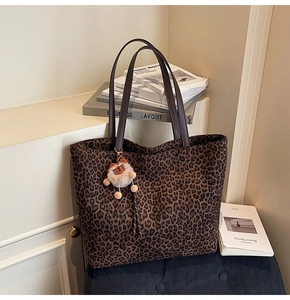 Détail d'un sac cabas léopard avec anses en cuir marron et pendentif ours en peluche