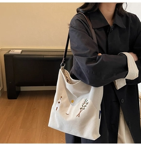 Detail of vintage beige canvas tote bag with floral embroidery and leather strap
