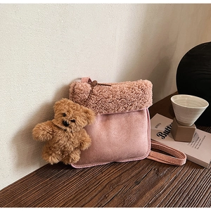 Detail of pink faux suede crossbody bag with fleece flap and a brown plush bear charm