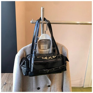 Close-up of black glossy patent leather shoulder bag with silver hardware and buckles