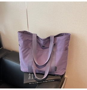 Detailed shot of purple canvas tote bag with metal buckle on a black chair and art books