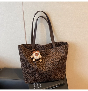 Détail du sac cabas léopard avec anses marron et un joli pendentif en peluche doux