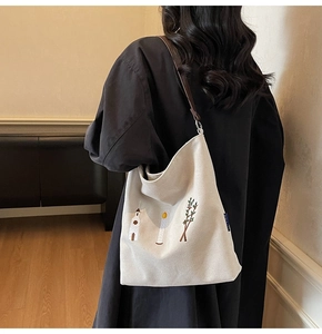 Detail of embroidered canvas tote bag with leather straps on a person for daily commute