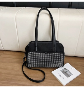 Close-up of black canvas handbag featuring sparkling rhinestone fringe and leather handles