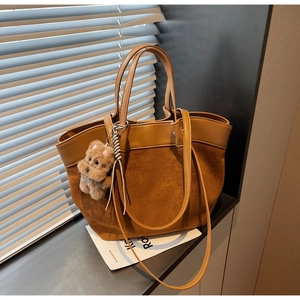 Detail of caramel suede and leather patchwork tote bag with cute plush puppy charm