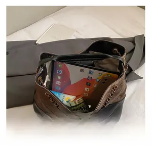 Detail of spacious interior of quilted chain tote bag holding a tablet and cosmetics