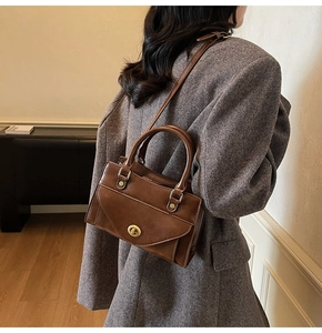Detail of vintage brown leather handbag with gold twist lock and elegant top handle strap