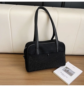 Detail of black knotted shoulder bag with silver rhinestones on a wooden table