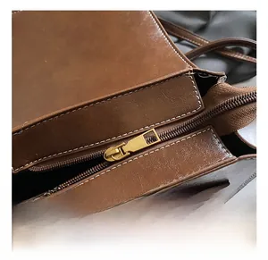 Close-up of vintage brown bag with white contrast stitching and gold metal hardware detail