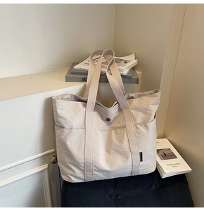 Detail view of large cream canvas tote bag with functional side pockets and woven handles