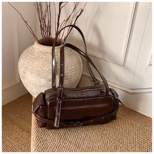 Close-up of retro dark brown glossy shoulder bag with metal eyelets and zipper pockets