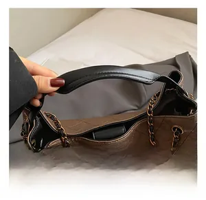 Detail of dark brown quilted tote bag showing wide leather handle and chain strap