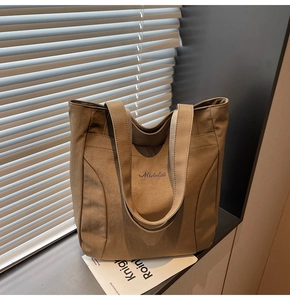 Close-up of khaki canvas tote bag featuring embroidered logo and reinforced shoulder straps