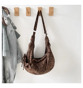 Detail of leopard print hobo bag hanging with side drawstring and soft fabric texture