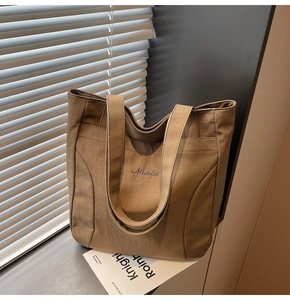 Detail view of the khaki canvas tote bag showing the Midolai logo and sturdy sewing