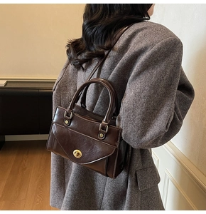 Deep brown vintage leather handbag shown on model's side with a grey wool coat