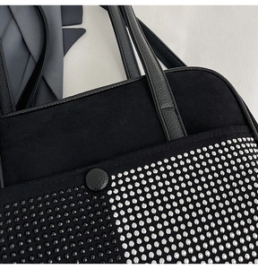 Detail of black suede bag with silver rhinestones, metal studs and lychee leather handle