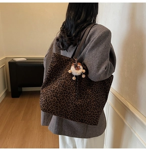 Detail view of large leopard print tote bag with brown straps and plush lamb charm