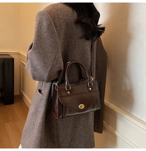 Detail of vintage dark brown leather crossbody bag with gold buckle on a model