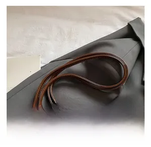 Detail view of brown faux leather handbag with retro metal buckle and decorative silk scarf
