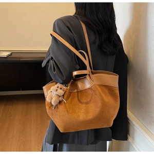 Detailed back view of a brown suede tote bag with a cute teddy bear charm on the shoulder strap