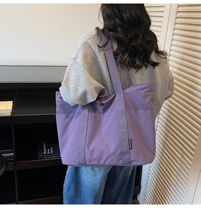 Detail of purple nylon tote bag with metal snap button and brand label worn on shoulder