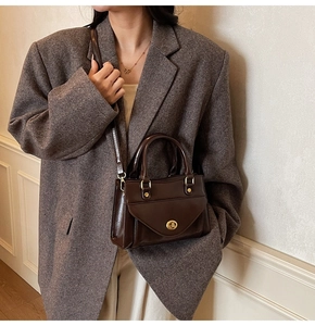 Detailed view of deep brown glossy leather bag with metal twist lock and slim shoulder strap