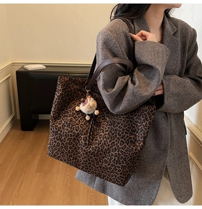 Détail macro du grand sac cabas à motif léopard avec breloque en peluche et anses en cuir
