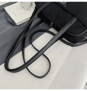 Close-up of black shoulder bag featuring decorative silver rivets and textured leather straps