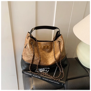Detail of quilted two-tone shoulder bag featuring bronze metallic finish and metal turn-lock