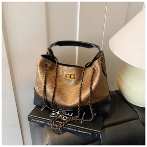 Detail of the vintage gold and black quilted leather bag with a metal chain and twist lock