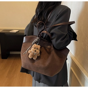 Brown suede tote bag with leather trim and plush bear charm shown on model back