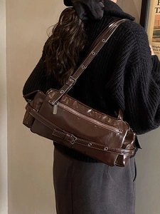 Deep brown glossy shoulder bag with vintage buckle on model for an autumn vibe