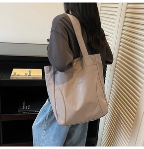 Close-up of model wearing a large canvas tote bag with elegant letter embroidery