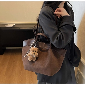 Detailed view of brown matte leather tote bag with a cute plush dog charm accessory