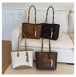 Detail of four retro tote bags with leather textures, gold logos and wooden bead charms