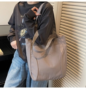 Detail of taupe canvas tote bag with embroidery, wide shoulder straps and textured fabric