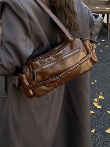 Brown high-gloss shoulder bag in retro utility style with silver zippers on a model
